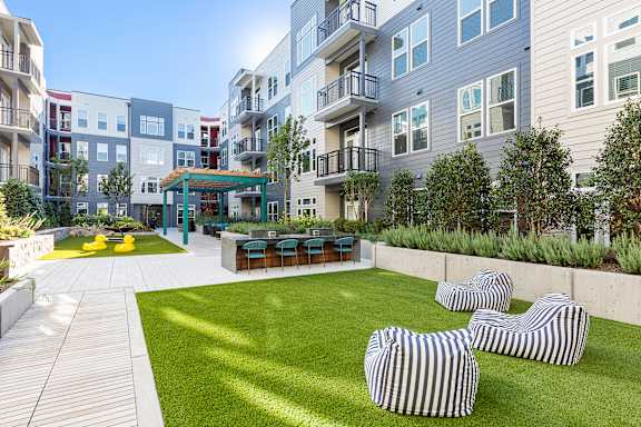 A modern outdoor living space with striped couches and a green area.
