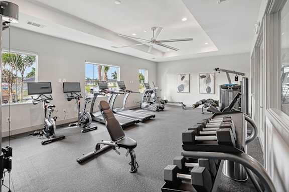 A spacious gym with a variety of equipment including treadmills, stationary bikes, and weight machines.