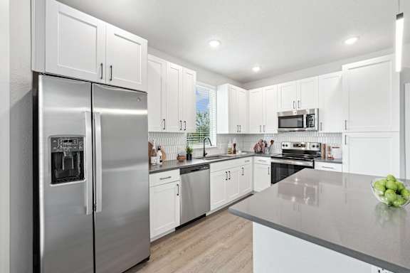 A modern kitchen with a stainless steel refrigerator and white cabinets.