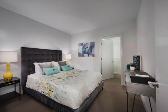 A bedroom with a large bed and a nightstand with a lamp.