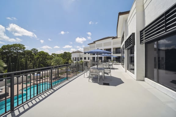 a balcony with tables and chairs and a swimming pool