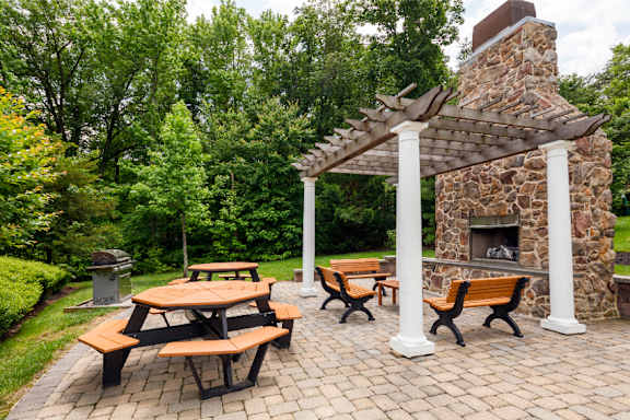 A patio with a stone fireplace and wooden benches.