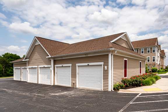 A two-car garage with a brown roof and white doors is situated in a parking lot.