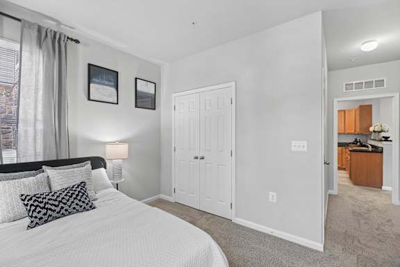 A bedroom with a large bed and a view of a city street through the window.