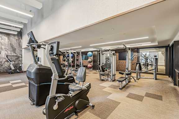 A gym with a variety of equipment including treadmills, weights, and exercise machines.