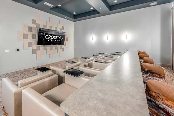 A conference room with a long table and chairs, a carpeted floor, and a wall with a decorative panel and a sign that reads "CROSSING AT PALM AIR".