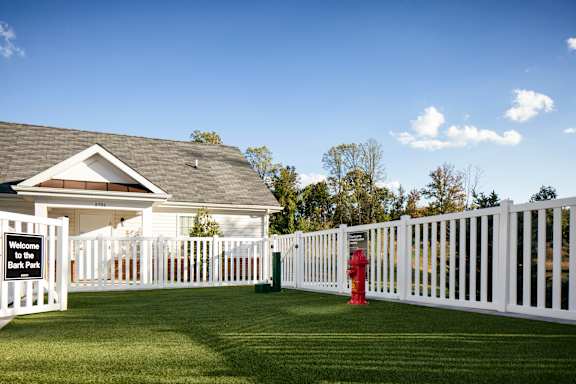 A white picket fence surrounds a building with a sign that reads "Welcome to the Park.".