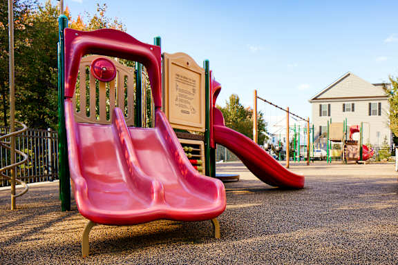 A playground with a red slide and a sign in the background.