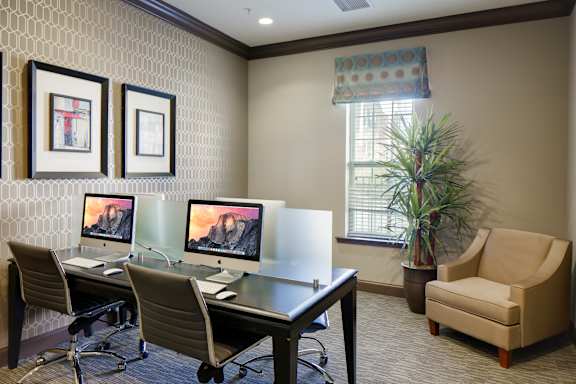 A room with a desk, chairs and computers.
