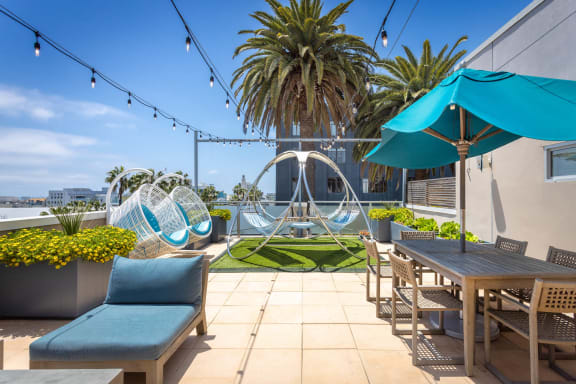 a patio with chairs and tables and a hammock in the middle of a grassy area