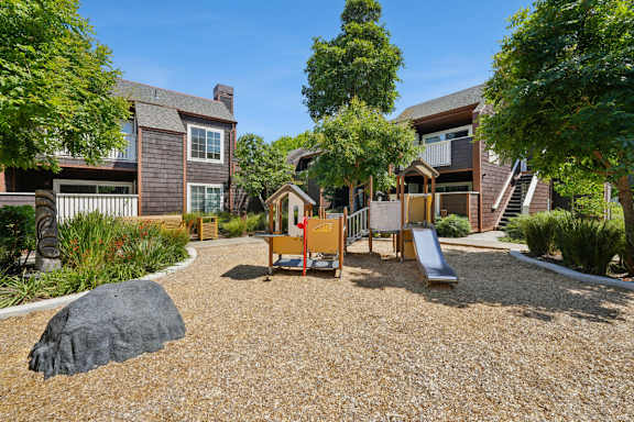 A playground area with a slide and a rock-like structure in the middle.