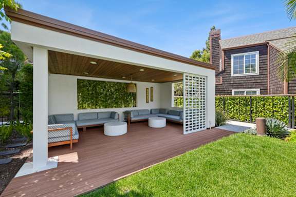 A white and brown patio with a white couch and a white table.