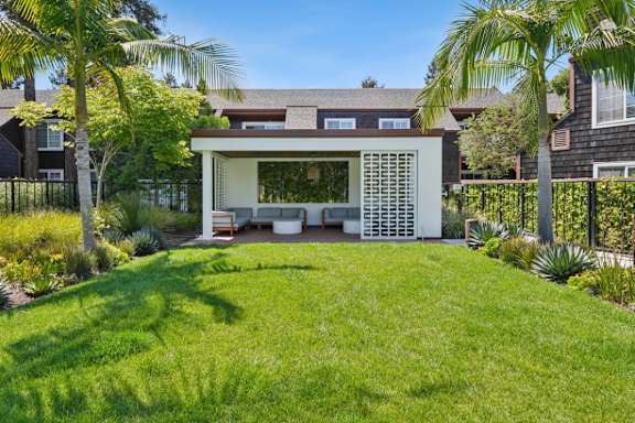 A modern house with a white exterior and a large lawn in front.