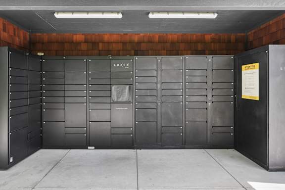 A row of black lockers with a yellow sign on the right.