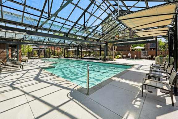 A large indoor swimming pool with sun loungers and a glass roof.