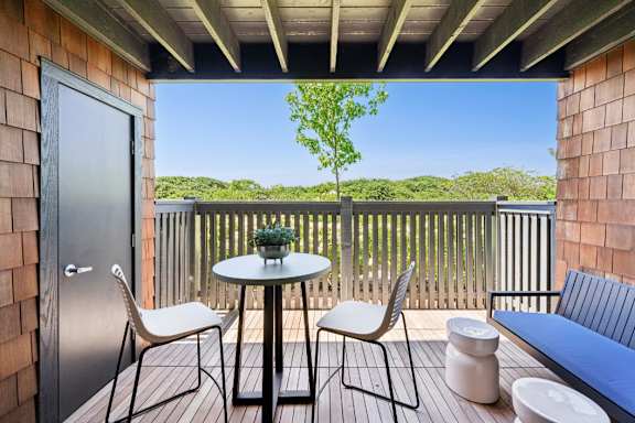 A small balcony with a table and chairs.