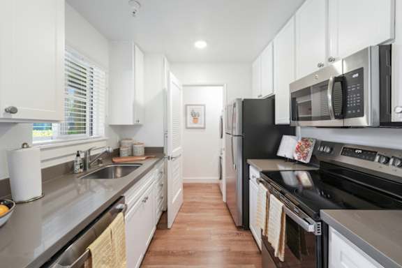 A kitchen with black appliances and white cabinets.