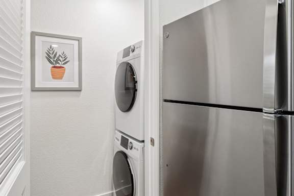 A picture of a plant is hanging on the wall above a washing machine.