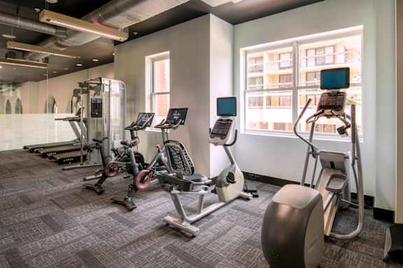 A gym with a variety of equipment including treadmills, stationary bikes, and elliptical machines.