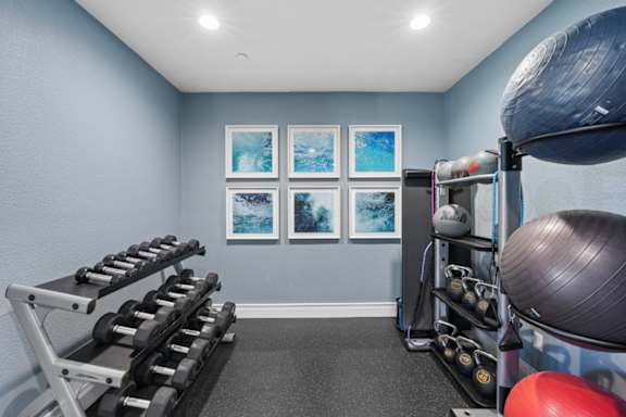 A home gym with a row of dumbbells, a bench, and exercise equipment.