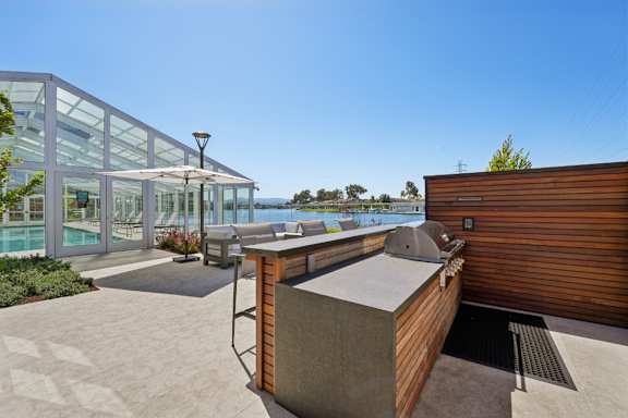 A modern outdoor kitchen area with a grill and a view of the ocean.