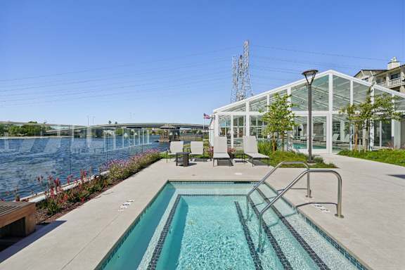 A pool with a metal ladder sits next to a river.