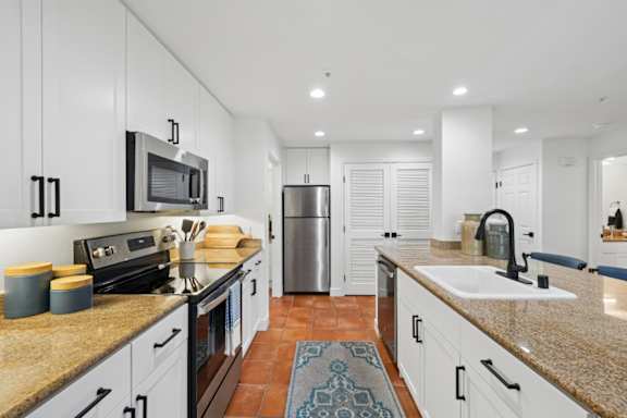 A kitchen with white cabinets and a tile floor.