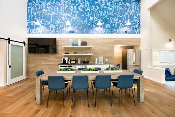 A dining room with a table and chairs and a blue wallpapered ceiling.