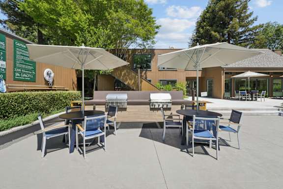 A patio with tables and chairs under umbrellas.
