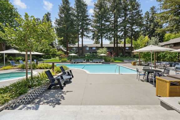 A pool surrounded by trees and chairs.