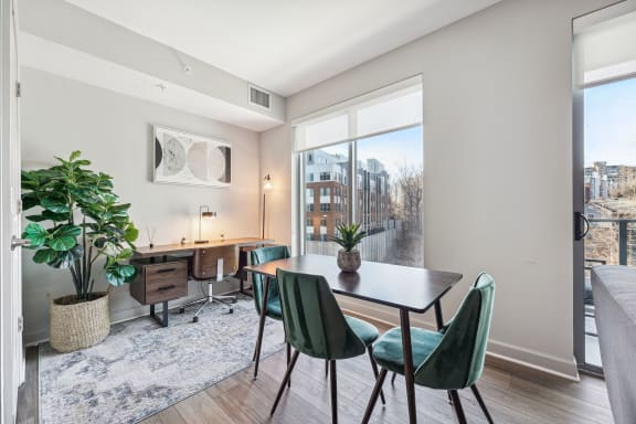 a dining room with a large window and a table with green chairs