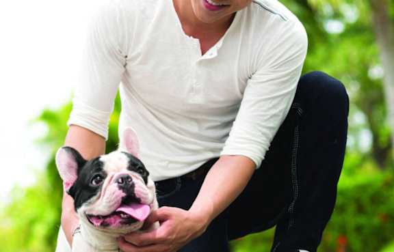 A person is holding a small dog with black and white fur.