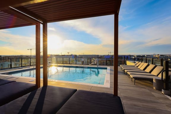 the pool at the top of a hotel with lounge chairs