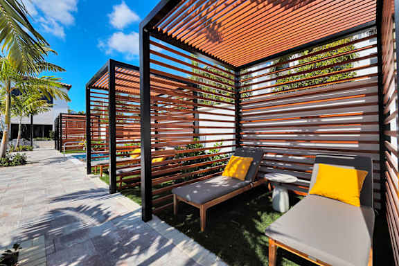 A patio with a bench and a table with a yellow pillow.