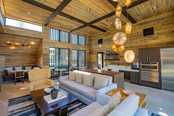 A modern living room with a wooden ceiling and a large grey couch.