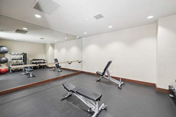 A gym with a variety of equipment including a bench press, a squat rack, and a medicine ball.