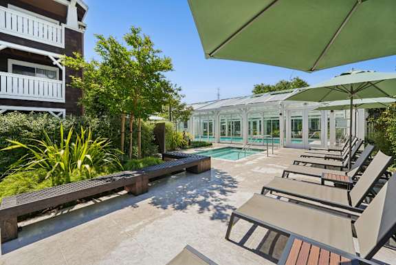 A sunny day at the poolside with lounge chairs and umbrellas.