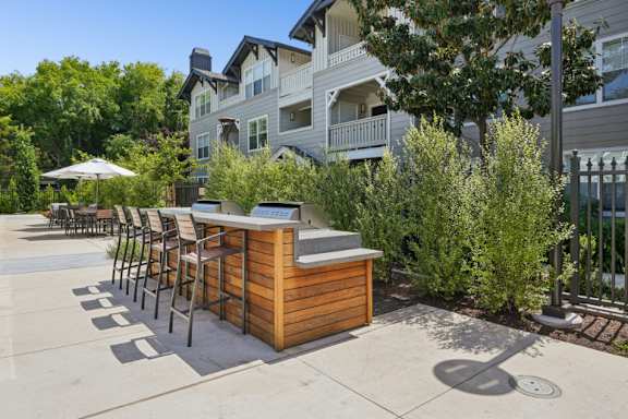 A wooden bar with stools is in front of a building.