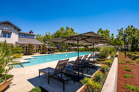 A pool area with a sun lounger and umbrella.