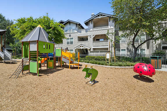 A playground with a green slide, a red ball, and a green and yellow play structure.