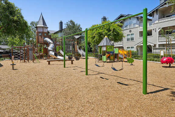 A playground with a green swing set and a red umbrella.