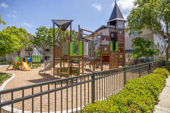 A playground with a wooden swing set and a green slide.