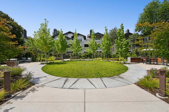 A large grassy area surrounded by a concrete walkway and trees.