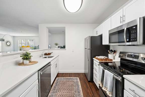 A kitchen with white cabinets and black appliances.