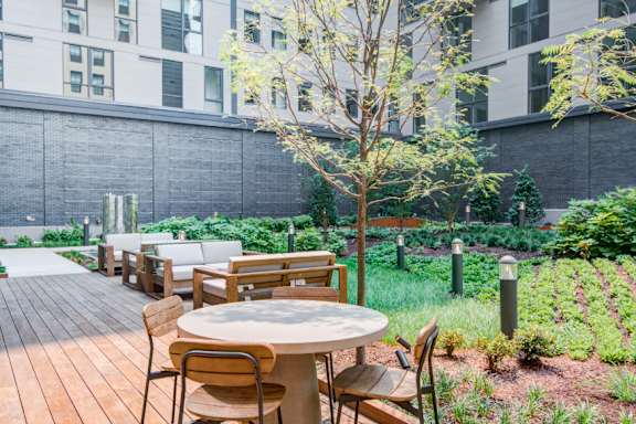 A wooden table with chairs is set up in a garden.