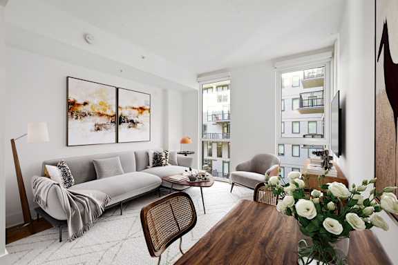 A living room with a grey sofa, a wooden table, and a painting on the wall.