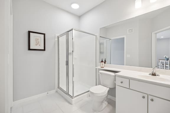 A white bathroom with a toilet, sink, and shower.