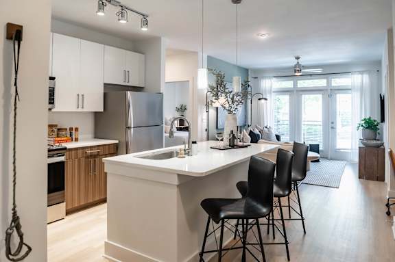 A kitchen with a white island and black chairs.