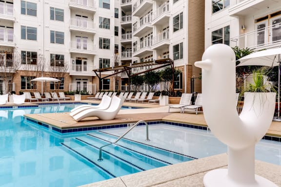 a swimming pool with a white duck statue in front of an apartment building