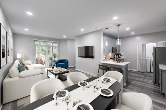 a living room and kitchen with white furniture and a tv